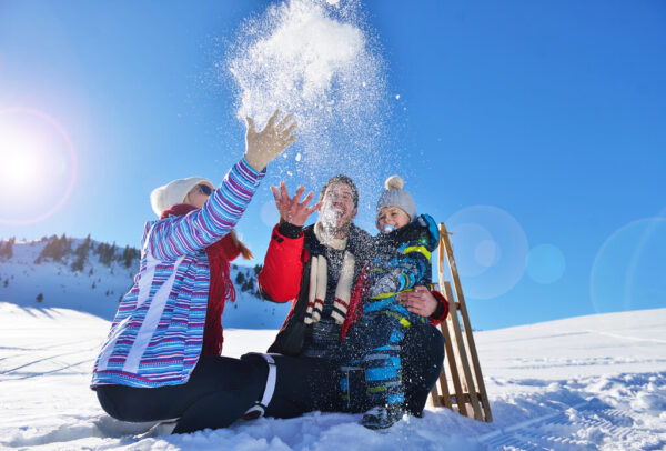 happy young family playing in fresh snow at beautiful sunny winter day outdoor in nature