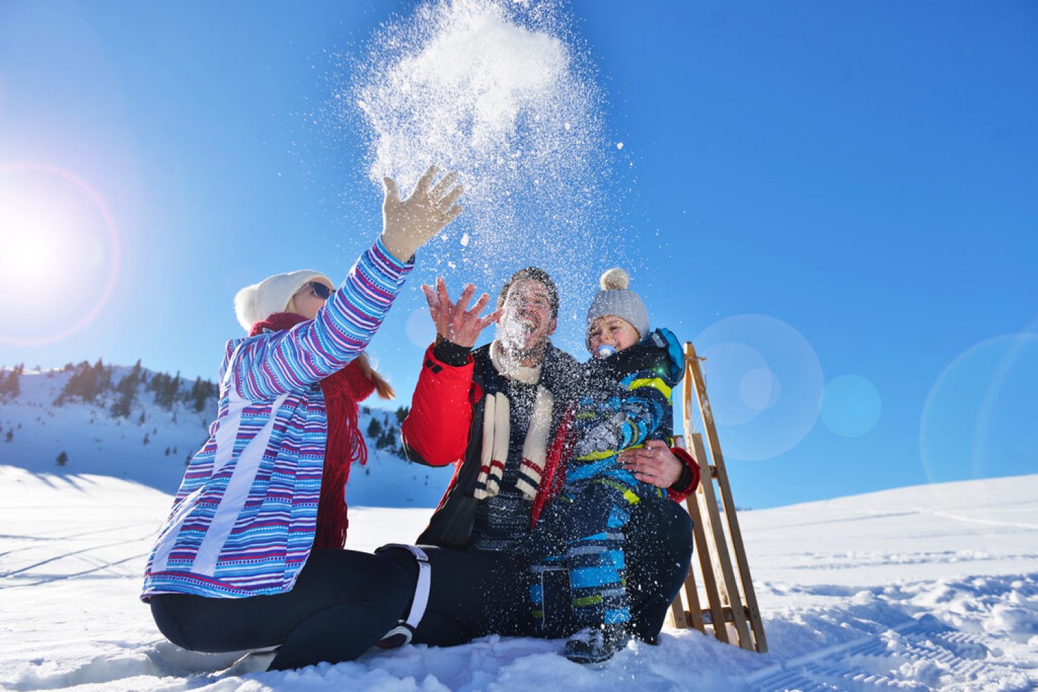 happy young family playing in fresh snow at beautiful sunny winter day outdoor in nature.